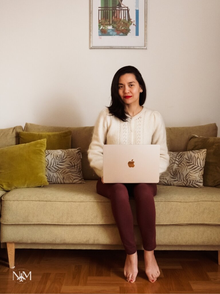 Beatrice on her nomadic stay in Montenegro, sitting with her MacBook laptop in the green living room